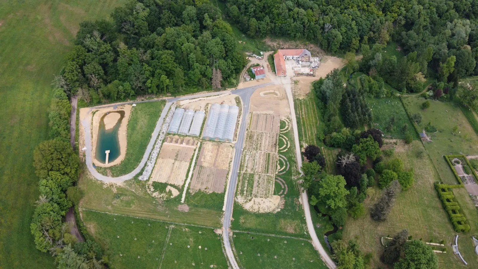 Vue aérienne du domaine : serres, planches de culture et étang